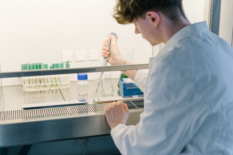 Ein Student sitzt im Labor an einem Experiment. 