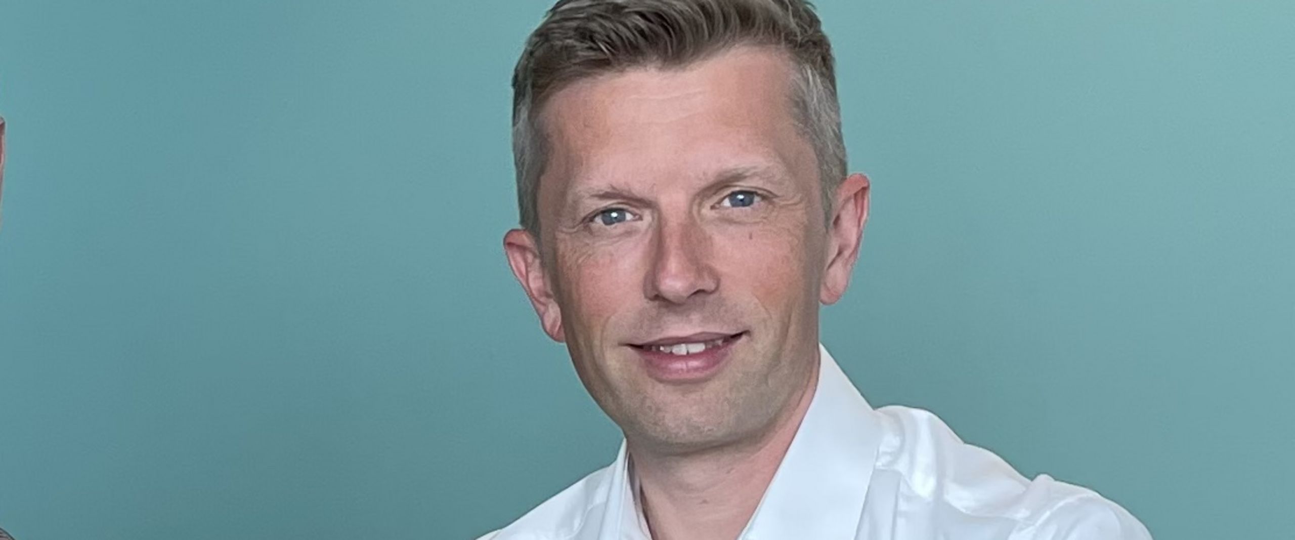 Dennis Kampen Sikora Dominik Uhr Zwei Männer sitzen am Tisch und alchen in die Kamera. Rechts von ihnen steht ein Laptop.