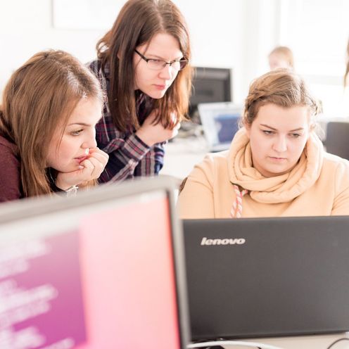 Drei Studentinnen programmieren am Laptop. 