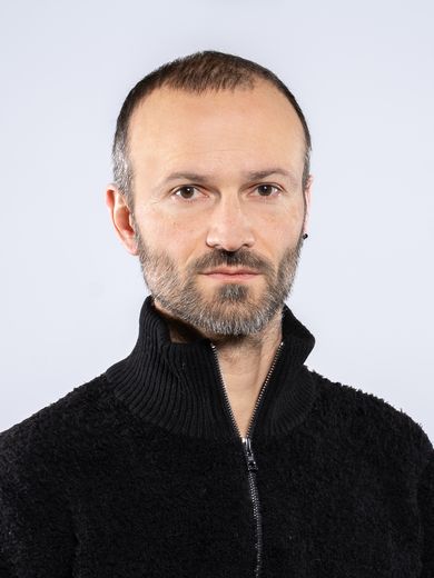 Auf dem Bild ist Philipp W&uuml;ndrich zusehen. Er hat kurzes schwarzes Haar und tr&auml;gt eine schwarze Rollkragen-Strickweste.