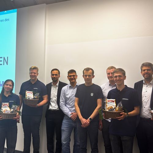 Gruppenbild mit Männern und Frauen vor einer Power-Point-Präsentation