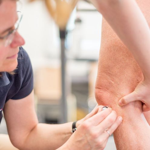 Eine Frau bringt einen Sensor am Knie einer Studentin an, um damit Bewegungen aufzuzeichnen.