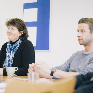 Teilnehmende eines Weiterbildungsseminar sitzen in einem Seminarraum.