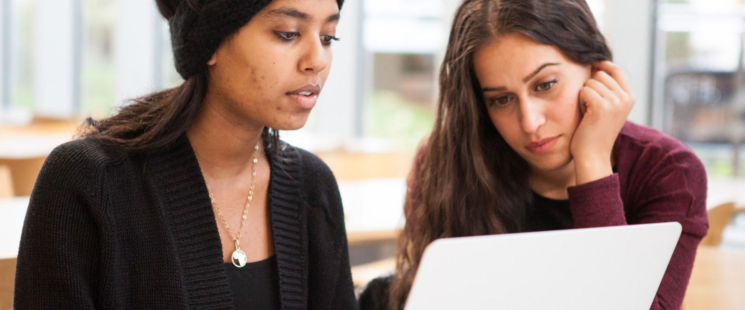 Studentinnen sitzen gemeinsam am Laptop