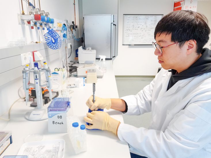 Mann sitz an einem labortisch mit Schutzhandschuhen und beschriftet Proben