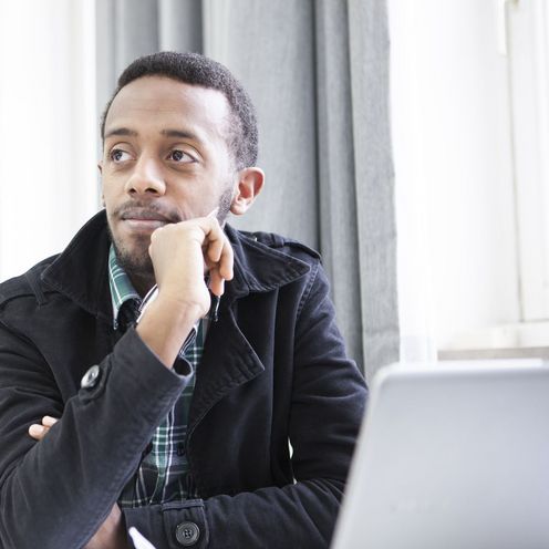 Ein Student sitzt nachdenklich vor einem Laptop in einem Seminarraum.