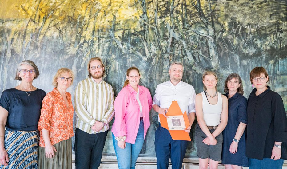 Acht Personen haben sich zu einem Gruppenfoto aufgereiht.