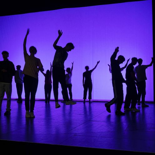 Schwarze Schatten auf einer B&uuml;hne im lila Licht.