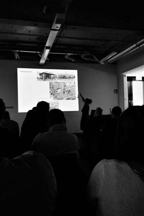 Ein Vortrag mit einem Beamer. Im Vordergrund sind zuhörende Personen.