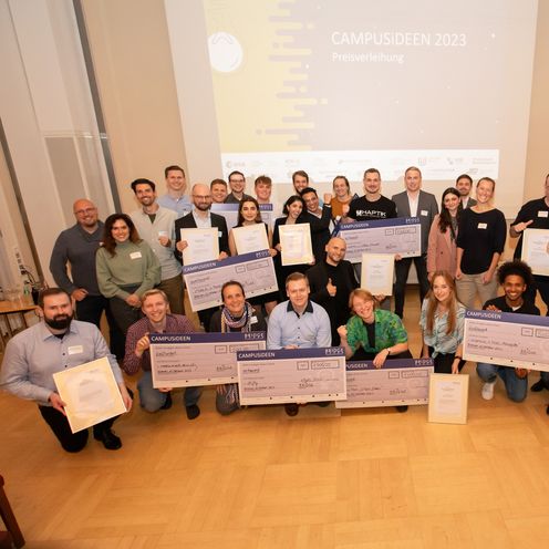 Gruppenbild mit jungen M&auml;nnern und Frauen. Sie halten jeweil &uuml;bergro&szlig;e Geldchecks