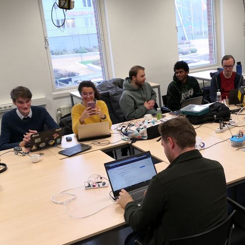 Studierende aus Bremen und Groningen sitzen mit Laptops an einem gro&szlig;en Tisch und arbeiten. 