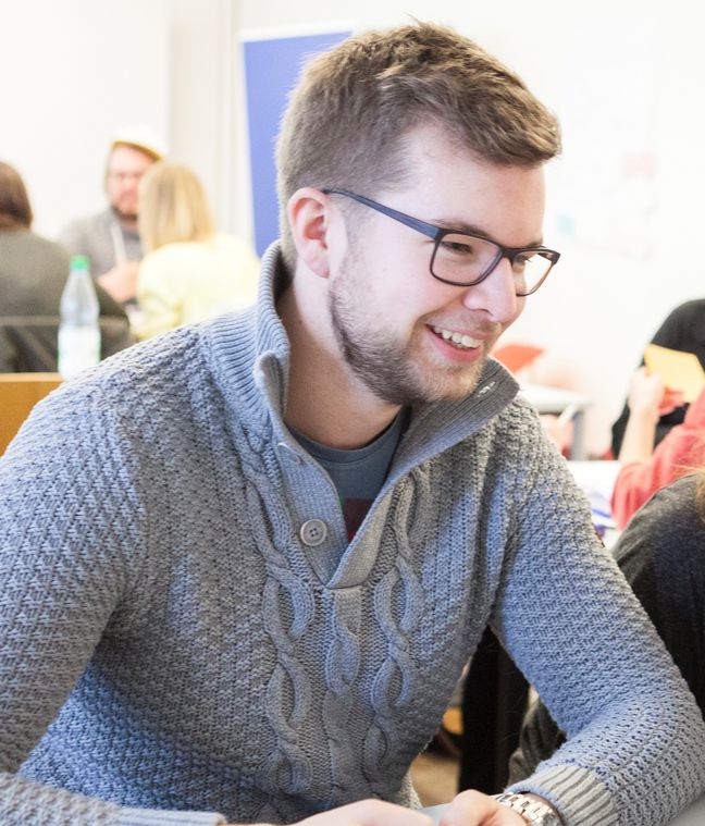 Student schaut l&auml;chelnd zur Seite.