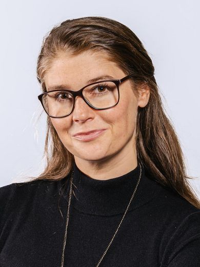 Auf dem Foto ist Merle Siedenhans zusehen. Sie hat lange dunkelblonde Haare. Sie trägt eine Brille und einen dünnen schwarzen Rollkragenpullover. 