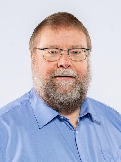 Auf dem Foto ist Oliver Riesener zusehen. Er hat kurze blonde Haare und einen grauen Bart. Er tr&auml;gt eine Brille und ein hellblaues Hemd. 