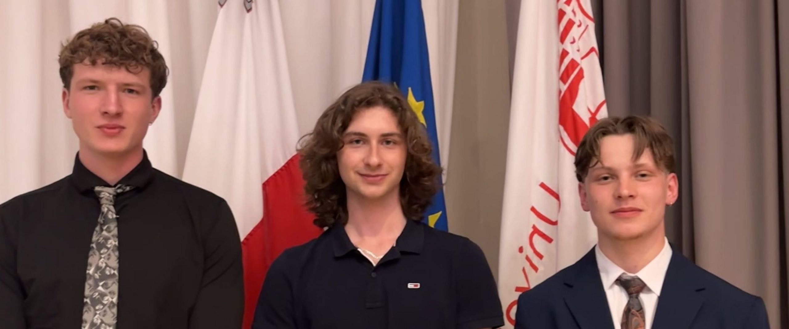 202605 STARS EU Student Board Conference Malta A group photo of three young men. They are standing in front of flags.