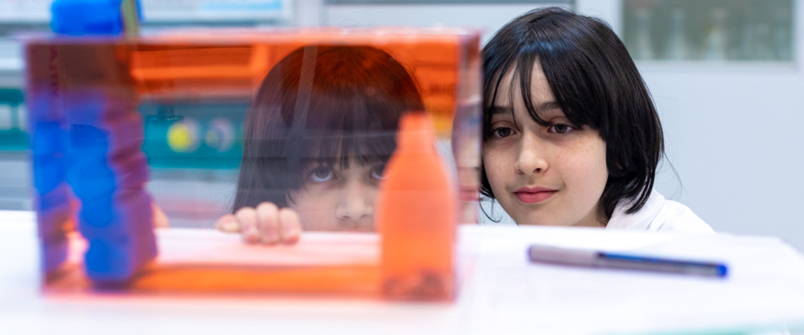 Zwei Kinder schauen in labor &uuml;ber eine Tischkante