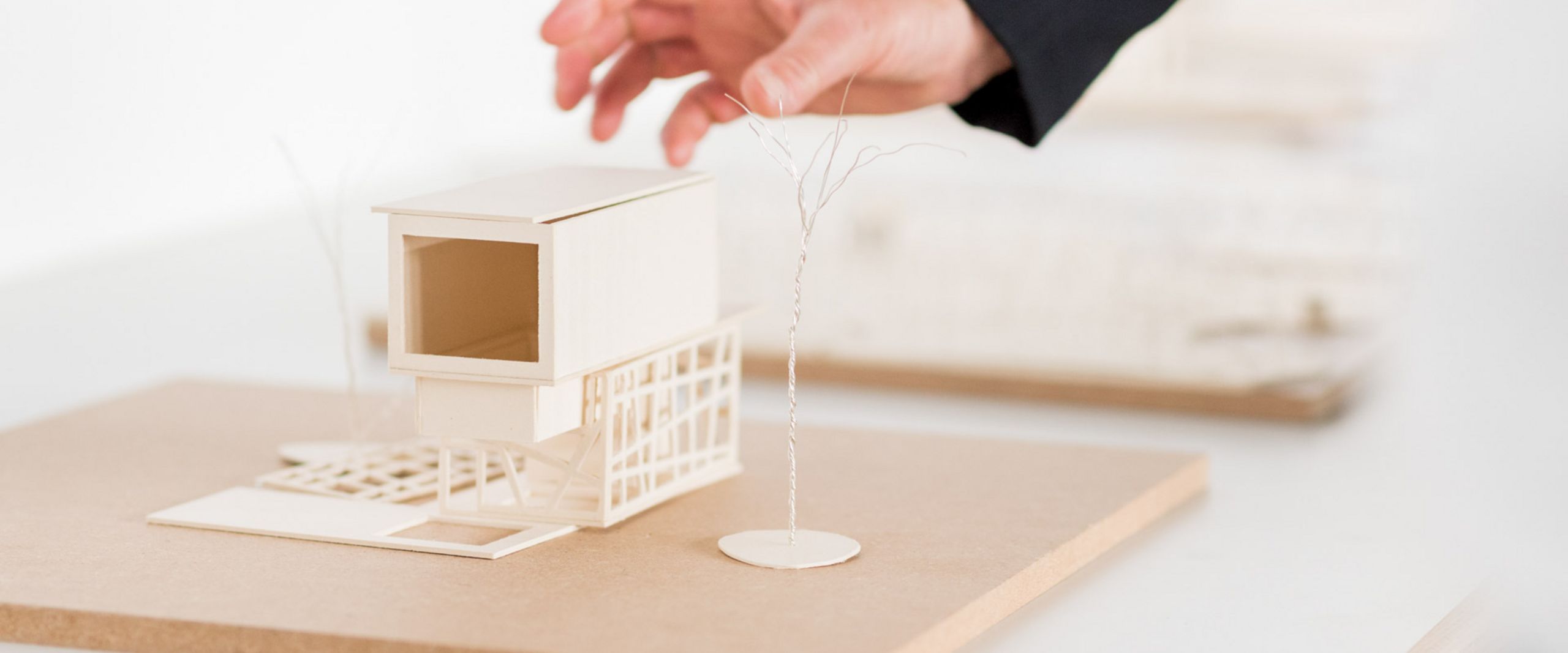 Eine Hand greift nach einem Modell eines Hauses.  Eine Hand greift nach einem Modell eines Hauses.