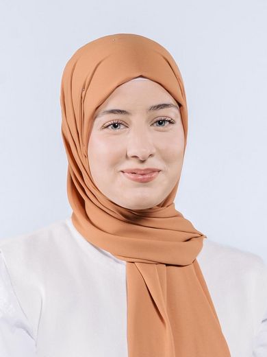Auf dem Foto ist Nurdane Irmak zusehen. Sie trägt ein aprikotfarbendes Kopftuch und eine weiße Bluse. 
