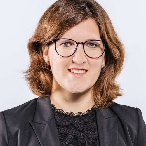 Kristina Lemmer Auf dem Bild ist Kristina Lemmer zusehen. Sie hat schulterlanges graues Haar und trägt eine schwarze Brille sowie eine schwarze Bluse unter einem schwarzen Blazer.