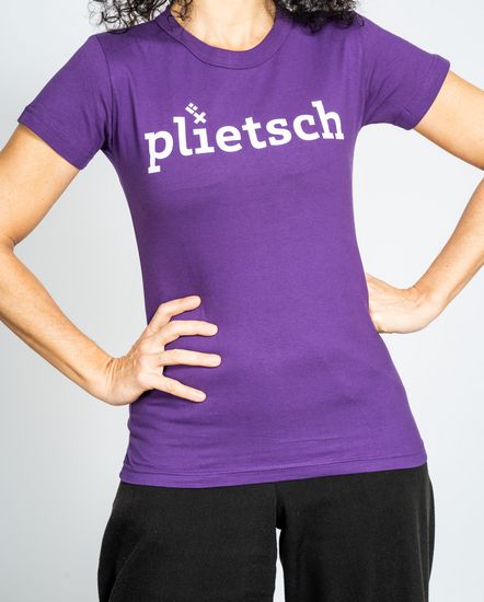Das Model trägt ein violettes T-Shirt für Damen mit der Aufschrift “plietsch“.