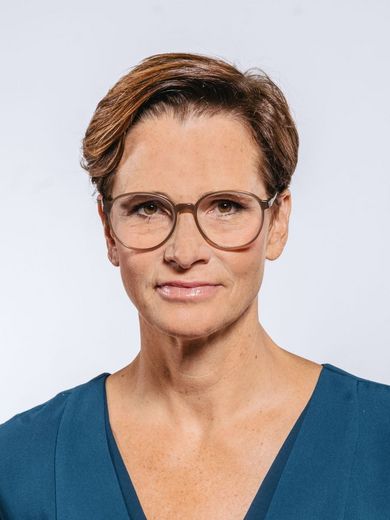 Auf dem Bild ist Ulrike Mansfeld zusehen. Sie hat kurzes braunes Haar und trägt eine Brille und ein blaues Oberteil. 