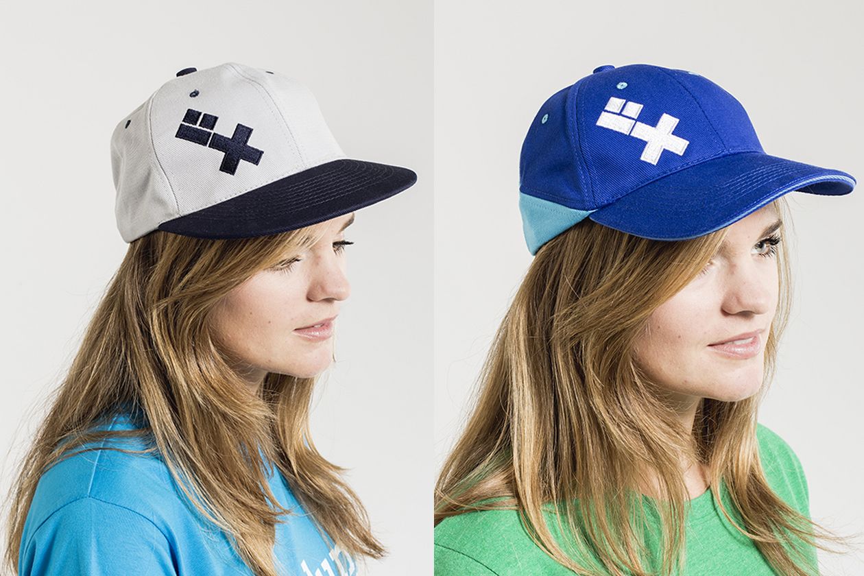 Ein Model trägt links eine grau-schwarze und rechts eine hell-/dunkel-blaue Cap mit HSB-Logo.