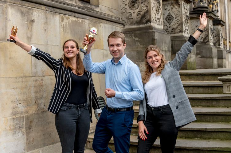 3 junge Gr&uuml;nder:innen jubelnd mit Pokal vor Sch&uuml;tting