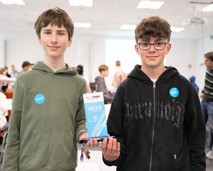 Zwei Jungs halten einen kleinen Pokal und schauen in die Kamera