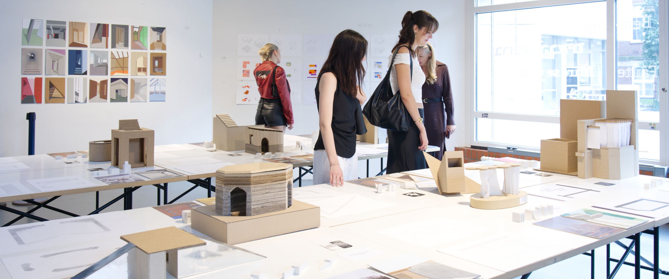 Pesonen schauen sich Bilder und Modelle auf Tischen an