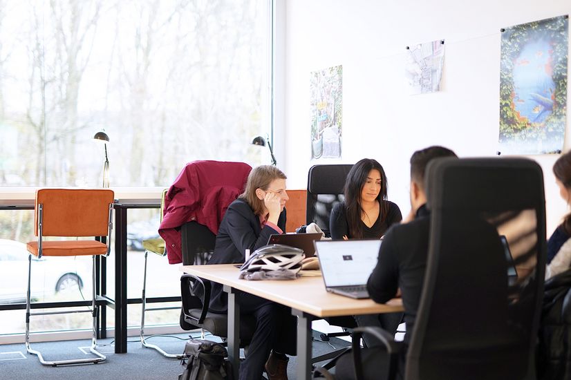 Prof. Dr. Brita Schemmann mit Studierenden an einem Tisch im Co-Working-Space