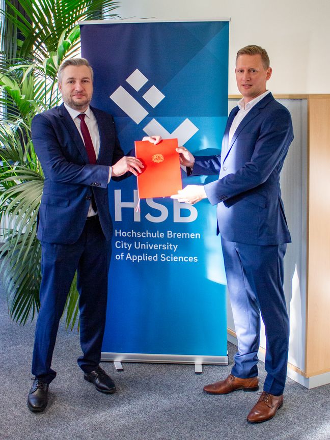 Kanzler Daniel Engelbrecht überreicht Professor Heiko Spekker seine Ernennungsurkunde.