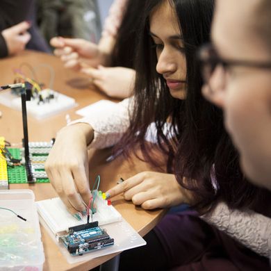Studentinnen bauen ein technisches Gerät mit Kabeln. 
