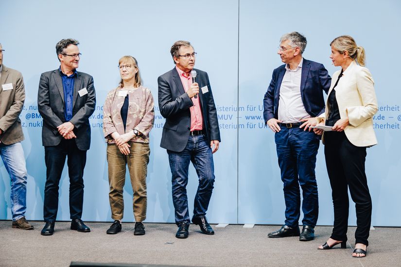 Prof. Dr. Martin Wittmaier spricht mit Vertreter:innen des Bundesumweltministeriums bei der Überreichung der Förderbescheide für das Projekt "Smart Recycling Up" in Berlin.