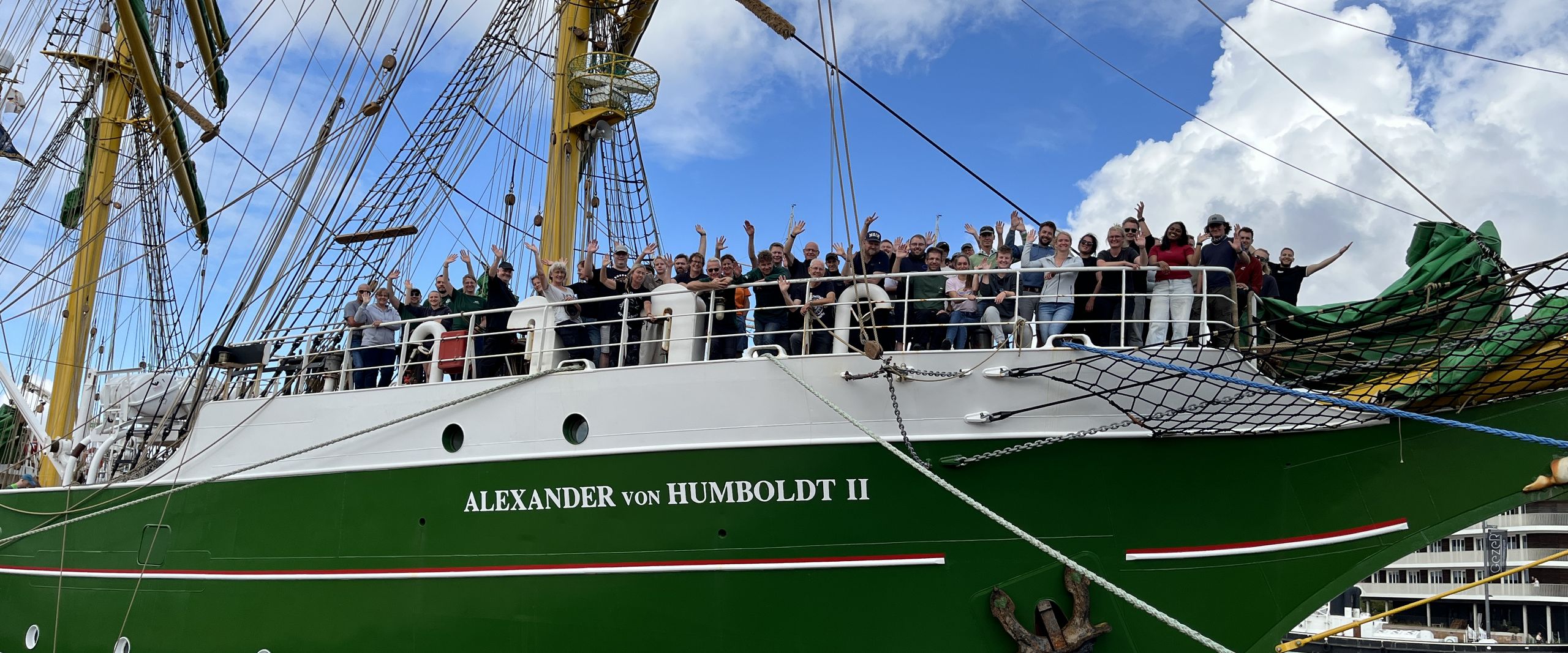 20260817 Alex-2 legt ab Segelschiff it grünem Rumpf. An Bord an der Spitze stehen Menschen und winken