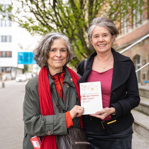 Margatee Zwei Frauen halten gemeinsam ein Buch und lächeln in die Kamera