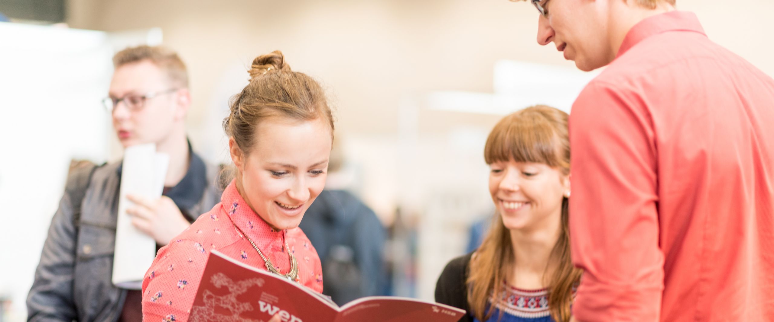 Junge Menschen im Gespr&auml;ch. Eine Frau schaut in eine Brosch&uuml;re.