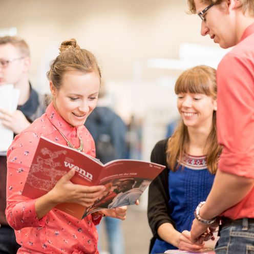 Junge Menschen im Gespr&auml;ch. Eine Frau schaut in eine Brosch&uuml;re.