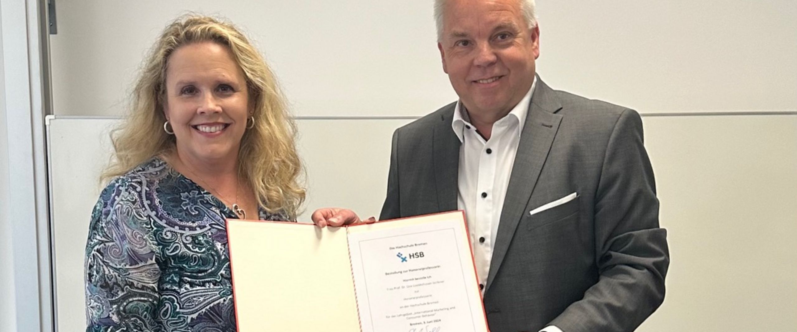 Frau und Mann halten eine Urkunde und schauen in die Kamera