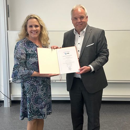 Frau und Mann halten eine Urkunde und schauen in die Kamera