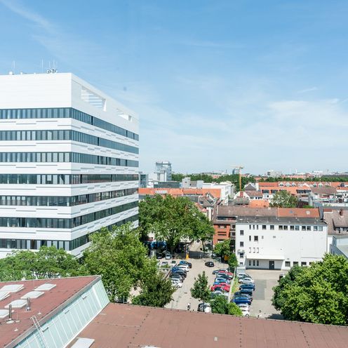 Auf dem Bild ist das AB-Geb&auml;ude des Campus Neustadtswall zusehen. Das Foto ist aus der Luft aufgenommen, sodass man au&szlig;erdem noch blauen Himmel, gr&uuml;ne B&auml;ume und einige Nebengeb&auml;ude und den Parkplatz erkennen kann. 