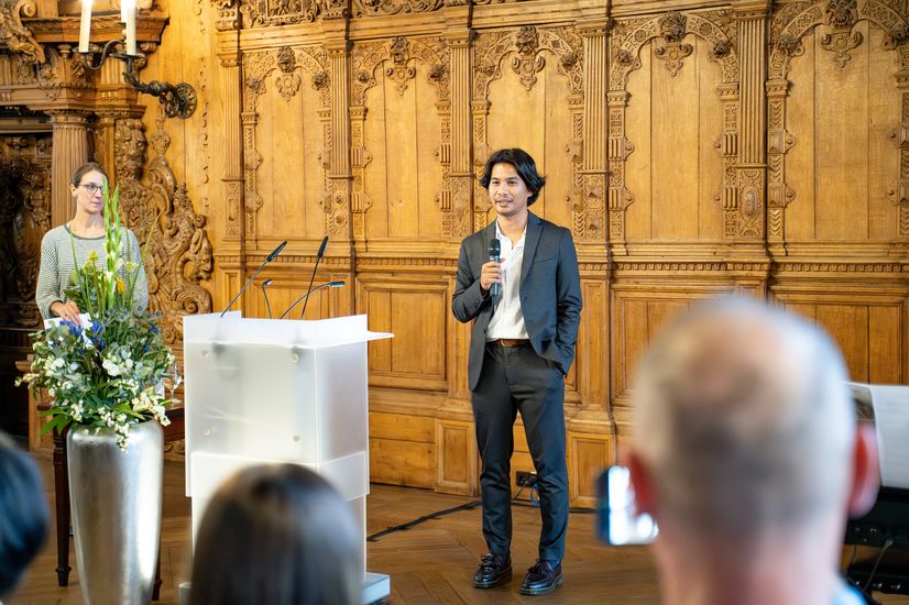 Young man gives speech in front of a large audience. 
