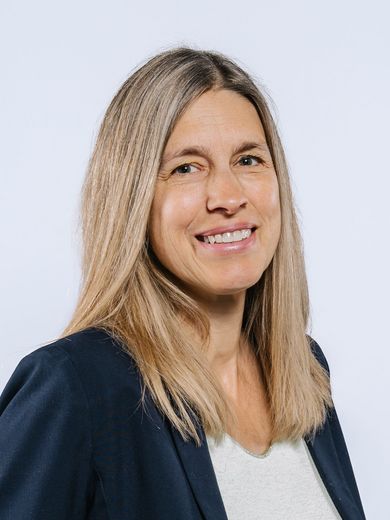 Auf dem Bild ist Dagmar Leuner zusehen. Sie hat langes blondes Haar und trägt ein weißes T-Shirt unter einem blauen Blazer. 