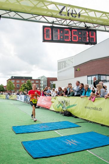 Ein L&auml;ufer auf der Strecke. An der Seite stehen mehrere Zuschauer.