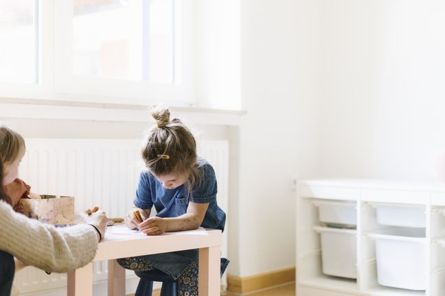 Kinder malen an einem kleinen Tisch