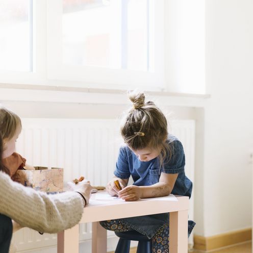 Kinder malen an einem kleinen Tisch