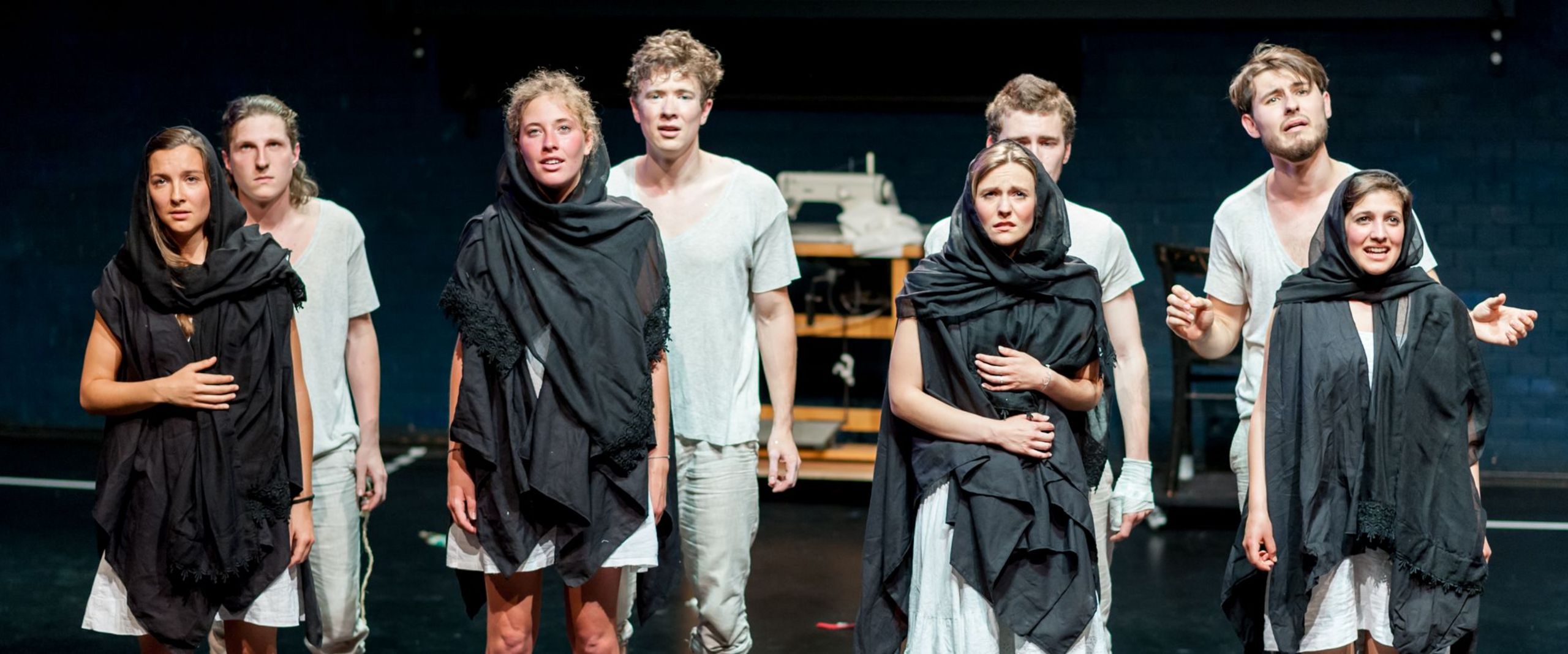 Bühnenszene aus dem Theaterstück "Peer Gynt" mit einer Gruppe Studierender in Pärchen aufgereiht.