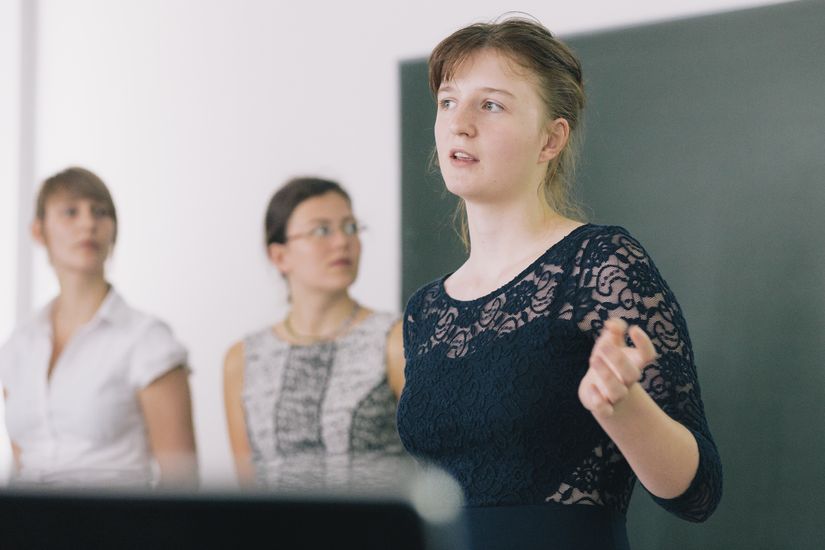 Studierende vortragend Studentin steht erklärend an Tafel
