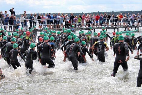 Schwimmer:innen in Neoprenanz&uuml;gen laufen ins Wasser beim M&uuml;ritz-Triathlon 2021.