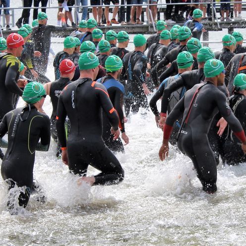 Schwimmer:innen in Neoprenanz&uuml;gen laufen ins Wasser beim M&uuml;ritz-Triathlon 2021.
