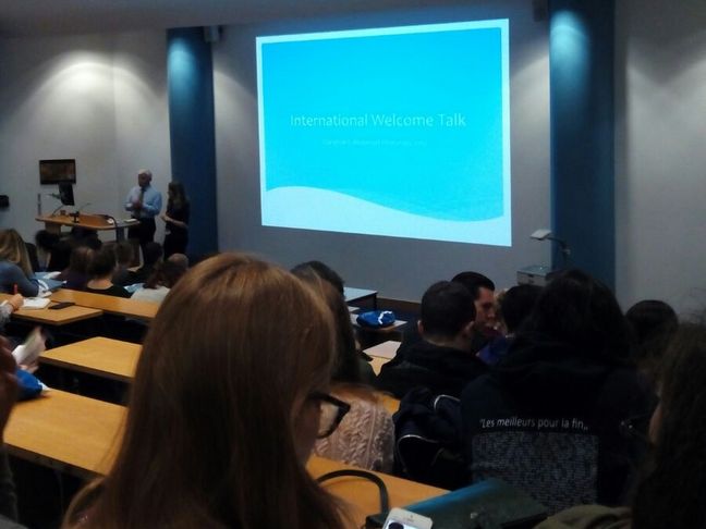 International Welcom Talk Das Bild zeigt einen Hörsaal aus Perspektive der Studierenden - mit Blick auf die Leinwand. Dort sieht man die Startfolie des International Welcome Talk an der Glasgow Caledonian University